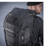 M-Tac Rygsæk Large Elite Hex Gen. IV henkilön selässä mustissa vaatteissa, näyttää kestävyyden ja tyylikkään muotoilun Cordura-materiaalissa.