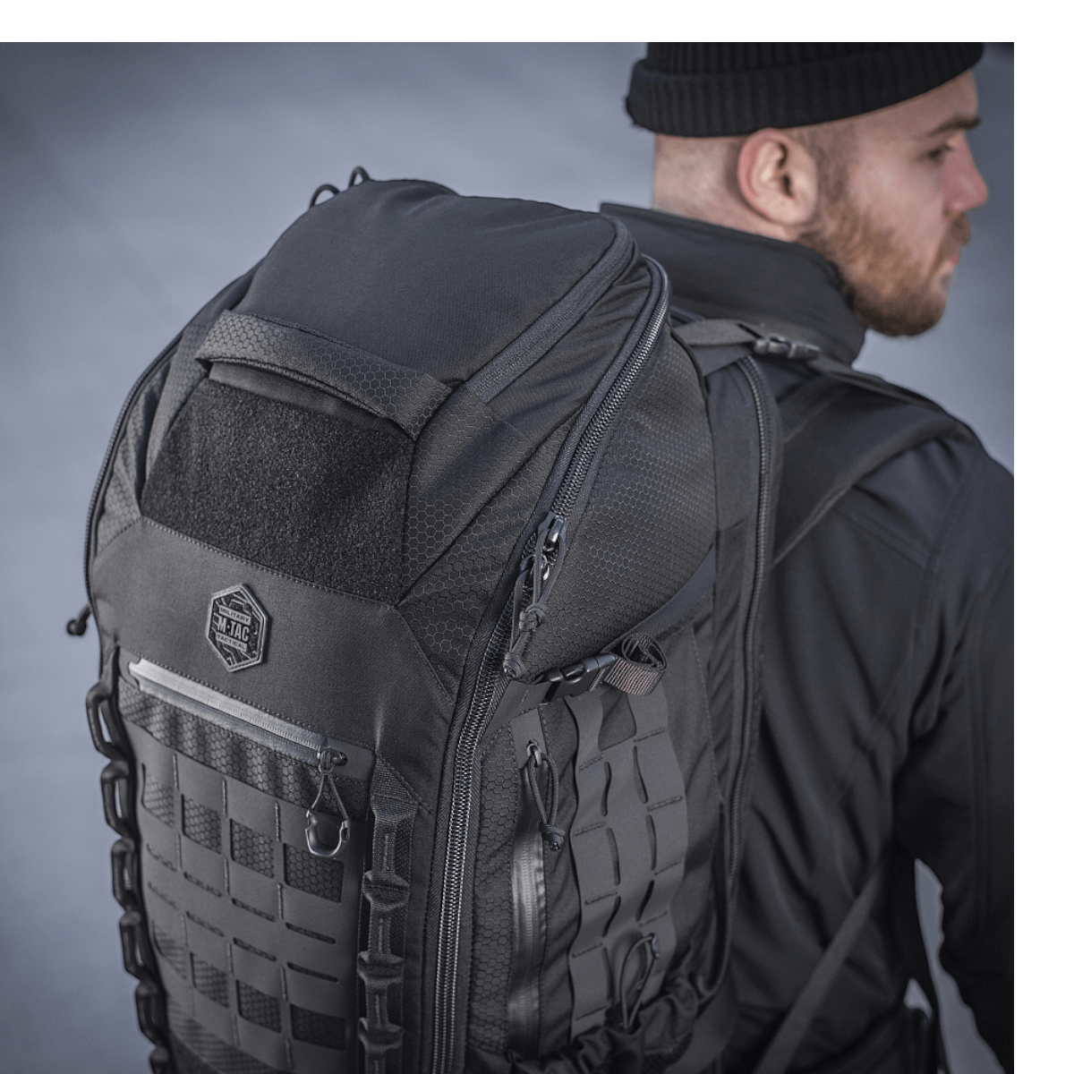 M-Tac Rygsæk Large Elite Hex Gen. IV henkilön selässä mustissa vaatteissa, näyttää kestävyyden ja tyylikkään muotoilun Cordura-materiaalissa.