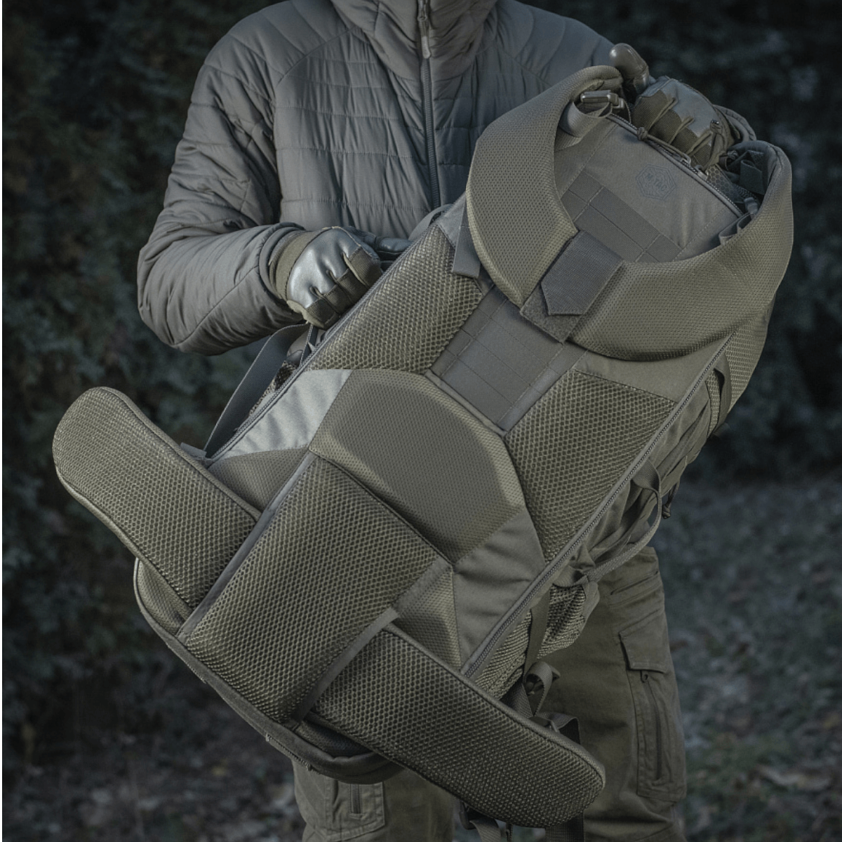 M-Tac reppu Large Elite Hex Gen. IV tukevasta Cordura-materiaalista, ergonominen muotoilu, esillä ulkoilmassa, kantajana henkilö.