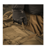 Käyttäjä hanskat kädessä pitää M-Tac reppu Large Elite Hex Gen. IV, tehty Cordura 500D- ja Hex 1000 -materiaaleista.