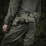 Mies pukeutuneena taktiseen varustukseen, M‑Tac Magasinsæk Dump Pouch Lite Elite kiinnitettynä vyöhön tehokkaaseen lippaiden käsittelyyn.