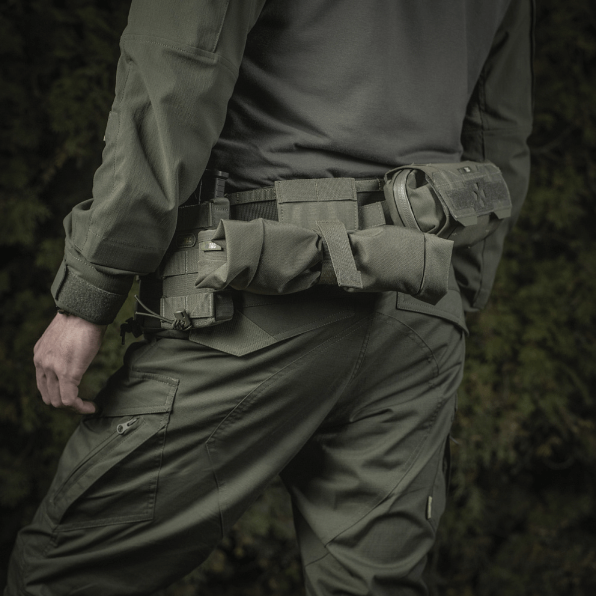 Mies pukeutuneena taktiseen varustukseen, M‑Tac Magasinsæk Dump Pouch Lite Elite kiinnitettynä vyöhön tehokkaaseen lippaiden käsittelyyn.