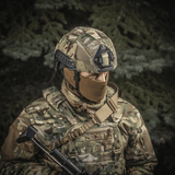 Sotilas pukeutuneena M‑Tac Hjelmcover Shroud Elite MULTICAM-maastokuviossa, suunniteltu TOR-D-kypärille tehokkaaseen naamiointiin maastossa.
