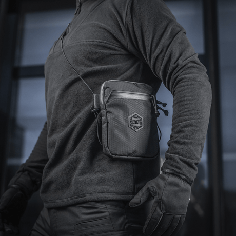 Henkilö M‑Tac Pocket Bag Elite HEX:n kanssa, kompakti laukku sopii EDC-varusteille ja avaimille, valmistettu kulutusta kestävästä materiaalista YKK-vetoketjuilla.