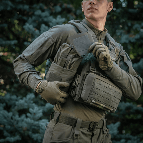 Mies kantaa M‑Tac Medic Pouch Vertical Large Eliteä kentällä luonnon taustalla.