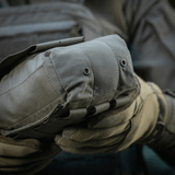 M‑Tac Medic Pouch Vertical Large Elite kestävässä Cordura 500D:ssä, lääkinnällisten välineiden turvallinen säilytys, pidettynä hansikkaisiin pukeutuneen henkilön toimesta.