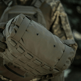 M-Tac Pouch Sukharka Gen.3 XL sotilaan pitelemänä metsäympäristössä; Cordura 500D, MOLLE-järjestelmä ja Velcro-paneli.
