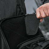 Henkilö osoittaa piilotetun aseen lokeroa M-Tac Tablet Bag Laser Cut Hexissä modulaarisilla inserteillä ja nopean pääsyn suunnittelulla.