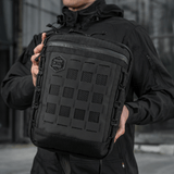 Mies pitää M-Tac Tablet Bag Laser Cut Hex -laukkua, valmistettu Cordurasta, Laser Cut MOLLE -paneeli edessä.