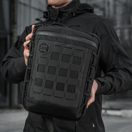 Mies pitää M-Tac Tablet Bag Laser Cut Hex -laukkua, valmistettu Cordurasta, Laser Cut MOLLE -paneeli edessä.