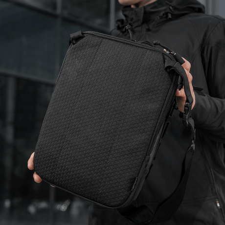 M-Tac Tablet Bag Laser Cut Hex, käytännöllinen Cordura-laukku Laser Cut MOLLE:lla ja piilotetulle aseelle tarkoitetulla lokerolla, nähty kädessä.