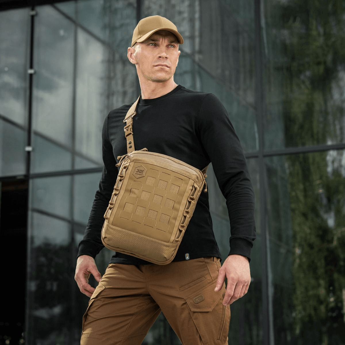 Mies kantaa M-Tac Tablet Bag Laser Cut Hex -laukkua Cordura-materiaalista Laser Cut MOLLE:lla, ihanteellinen EDC:hen, asiakirjoille ja tabletille.