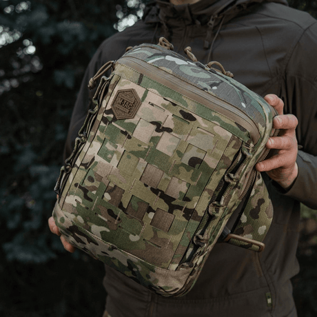 M-Tac Tablet Bag Laser Cut Hex camokuvioisena kädessä, etupaneeli Laser Cut MOLLE -järjestelmällä lisävarusteille.