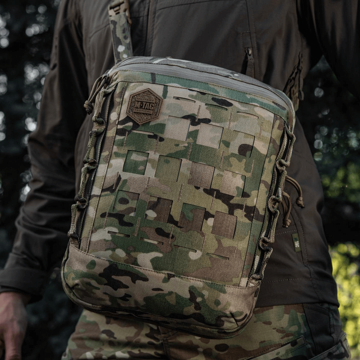 M-Tac Tablet Bag Laser Cut Hex maastokuvioinnilla, Laser Cut MOLLE ja kestävä Cordura-materiaali, kannettu henkilö toiminnassa luonnossa.