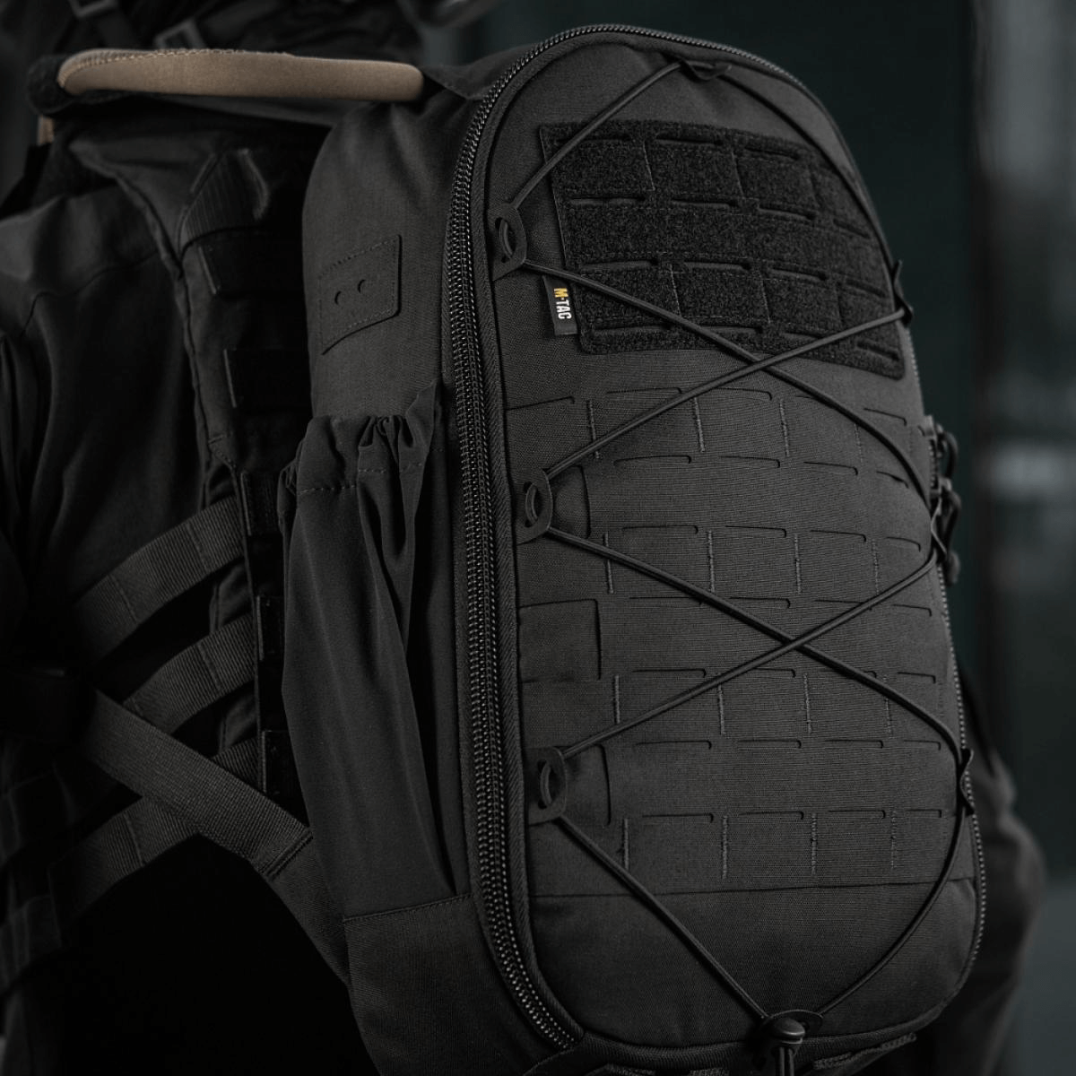 M-Tac STURM Elite -reppu MOLLE Laser Cut -muotoilulla ja Cordura-materiaalilla henkilön selässä, sivusta nähtynä.