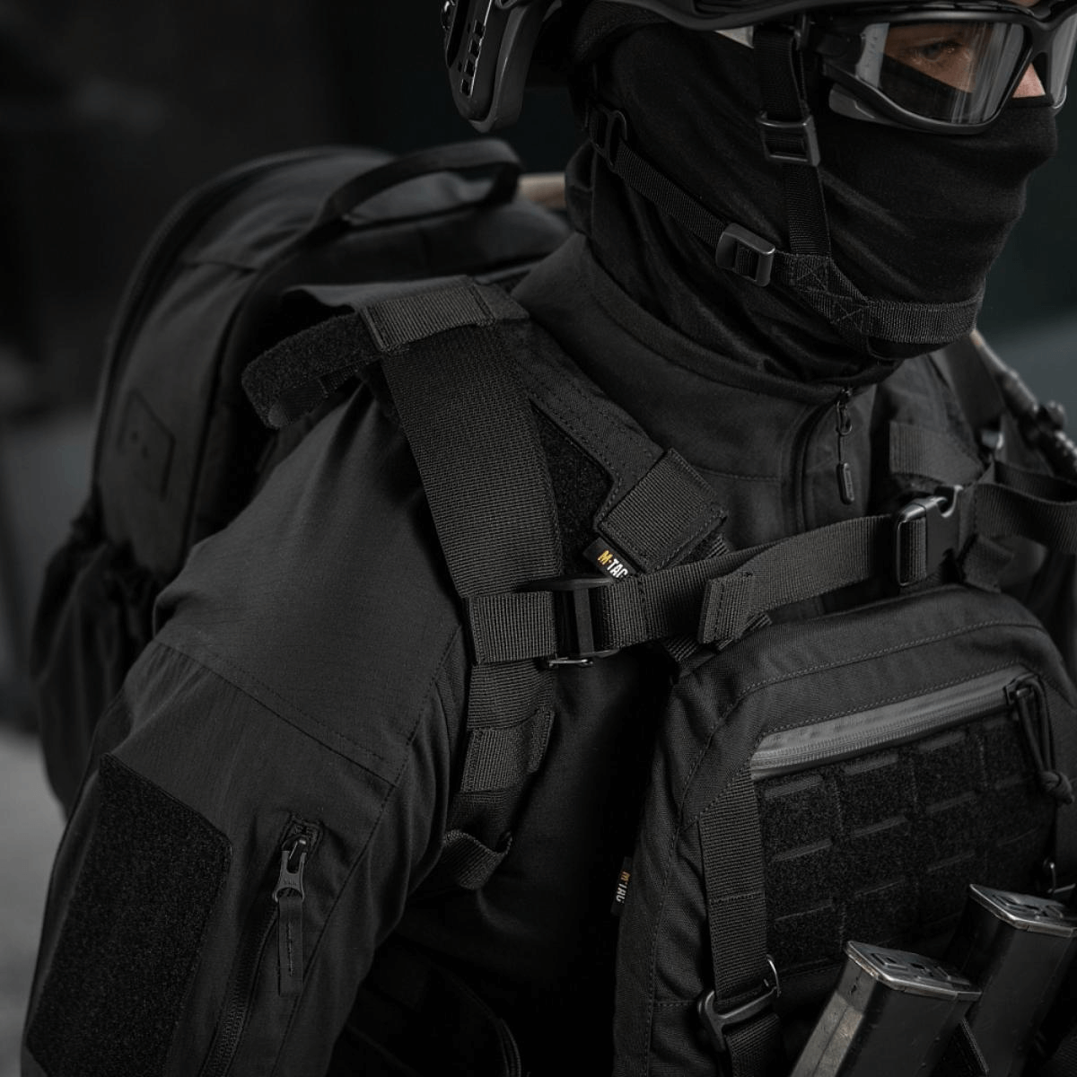 M-Tac STURM Elite -reppu henkilöllä taktillisissa vaatteissa, MOLLE Laser Cut -paneeli ja kestävä muotoilu lyhytaikaisiin kenttäoloihin.