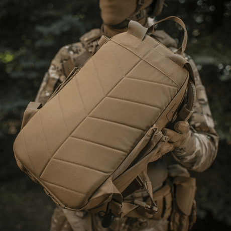 M-Tac STURM Elite -reppu pidettynä taktisesti pukeutuneen henkilön toimesta luonnossa, valmistettu Cordura-materiaalista.