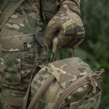 M-Tac STURM Elite -reppu camo-muotoilulla ja MOLLE-järjestelmällä, pidetty henkilön toimesta armeijavaatteissa ja taktisisissa käsineissä, 15 l tilavuus.