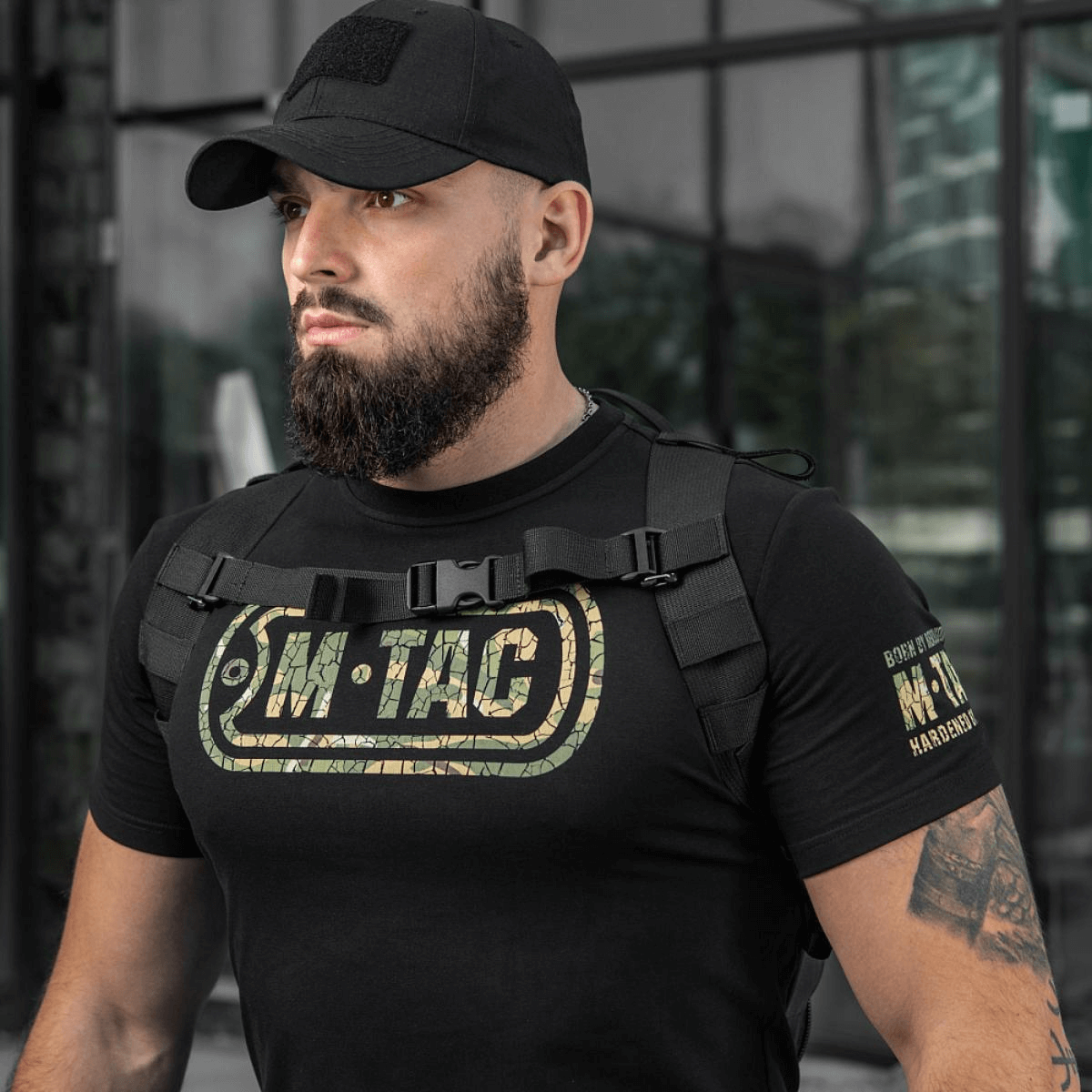 M-Tac STURM Elite -reppu kantohenkilöllä mustissa vaatteissa, valmis taktisiin tehtäviin. Kestävä ja monikäyttöinen lyhyille kenttäseikkailuille.