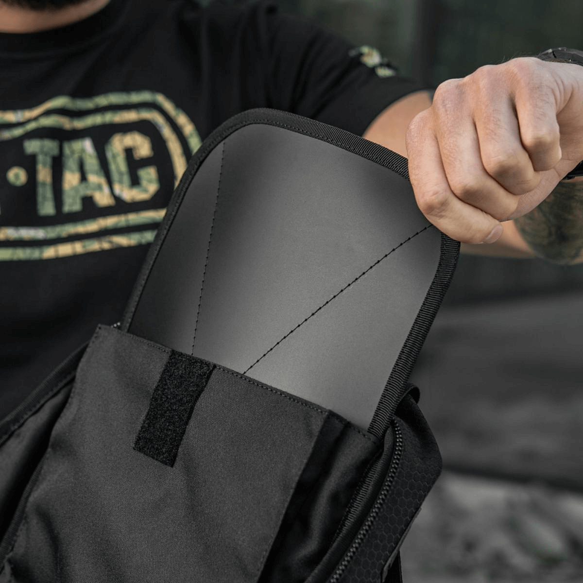 Henkilö esittelee M-Tac STURM Elite -reppua, jossa sisäänrakennettu selkätyyny ja MOLLE-järjestelmä, taktiseen varusteiden kantoon.