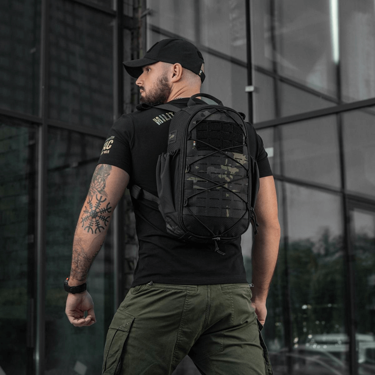 Mies kantaa M-Tac STURM Elite -reppua 15 l, musta väri, suunniteltu lyhytaikaisiin kenttäoloihin, MOLLE Laser Cut -paneelilla.