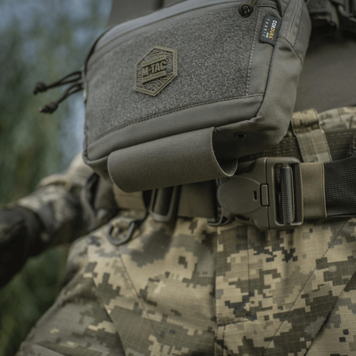 M-Tac Large Elite Gen.II olkalaukku sotilasasun päällä, lähikuva. Cordura 500D -materiaali, YKK-vetoketjut ja etu-Velcro-paneeli.