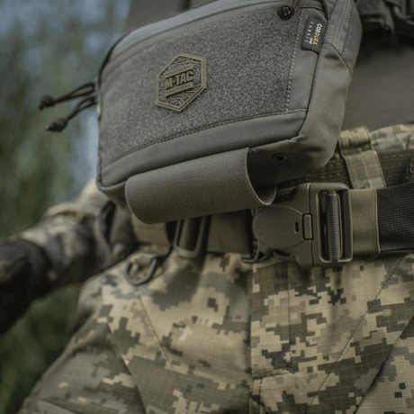 M-Tac Large Elite Gen.II olkalaukku sotilasasun päällä, lähikuva. Cordura 500D -materiaali, YKK-vetoketjut ja etu-Velcro-paneeli.