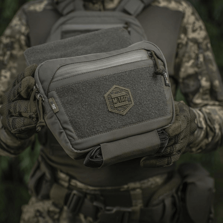 M-Tac Large Elite Gen.II olkalaukku Cordura 500D:stä YKK-vetoketjuilla, nähty taktisen maastovarustuksen yhteydessä.