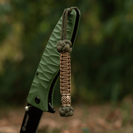 M-Tac Knife Lanyard Celtic, punottu paracord-veitsilisävaruste, korostaa tyyliä ja käytännöllisyyttä ulko- ja arkioloissa.