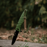 M-Tac Knife Lanyard Celtic - vihreä taittoveitsi punotulla paracord-lanyardilla ulkoilmassa.