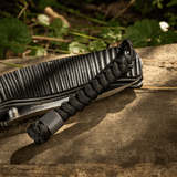 M-Tac Viper Lanyard Stainless Steel, punottu paracord ja Viper-helmi, tyylikäs veitsen lisä — musta lanyard puustaustalla.