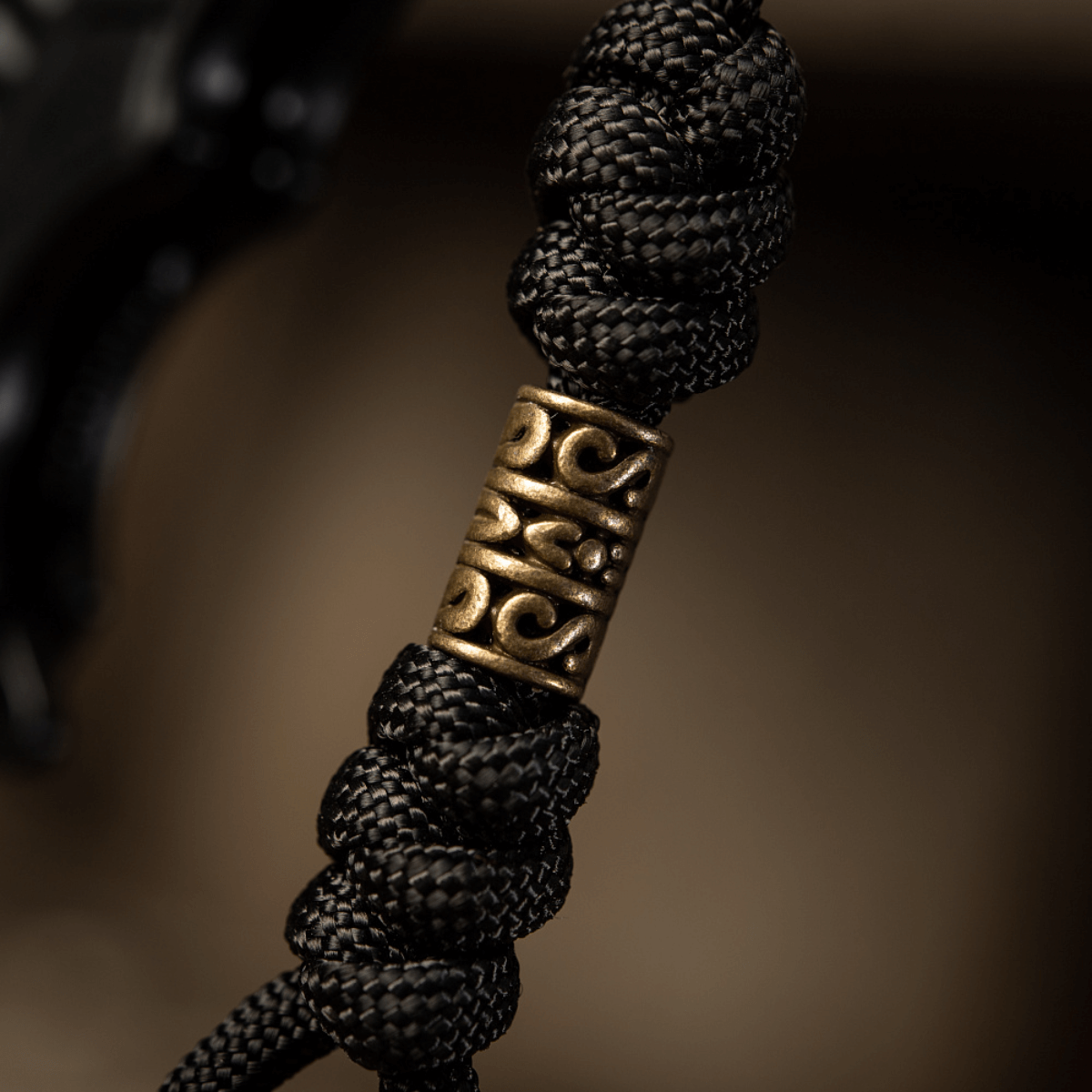 Yksityiskohtakuva M-Tac Zeus Lanyardista, punottu paracord ja koristeellinen messinkiosa, täydellinen veitselle ja varusteille.