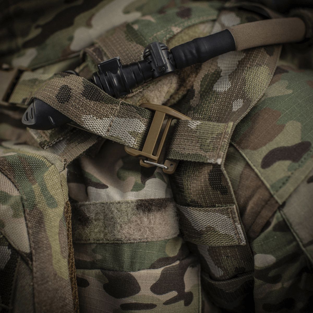 M-Tac reppu Sturm Elite Gen.II juomajärjestelmällä ja maastokuvioinnilla, lähikuva soljesta ja juomaletkusta.