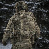 Sotilas kantaa M-Tac reppu Sturm Elite Gen.II lumisessa metsässä, MOLLE Laser Cut -järjestelmä ja joustonaru varusteille.