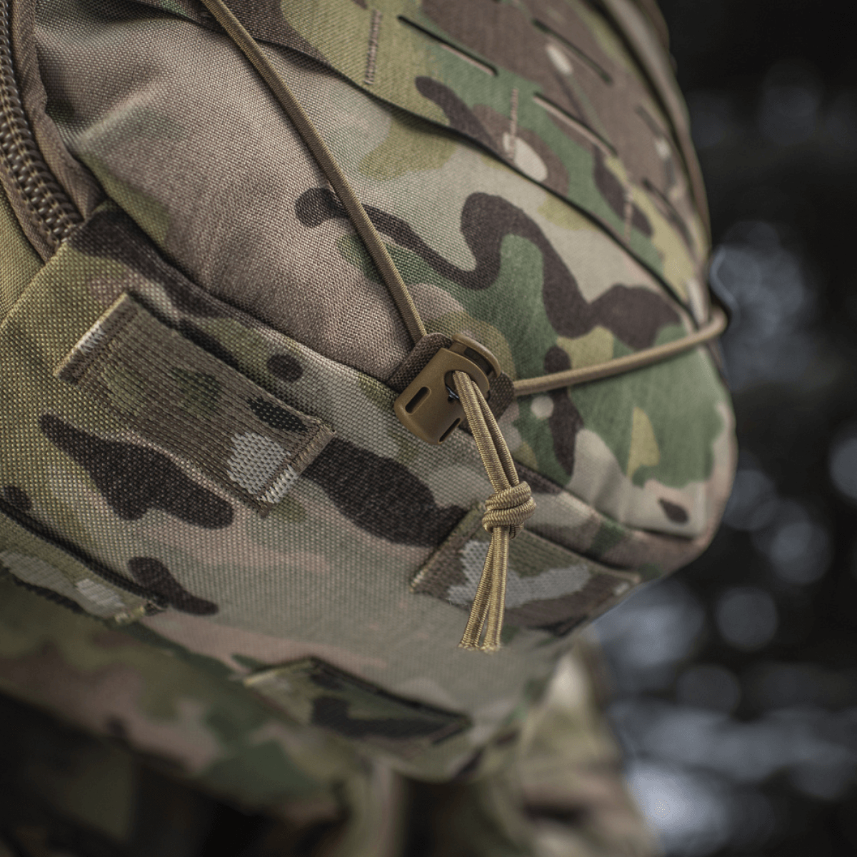 Lähikuva M-Tac reppu Sturm Elite Gen.II maastokuvioinnilla ja bungee-joustonarulla ulkovarusteille.