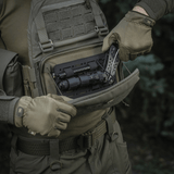 Henkilö avaa M-Tac Admin Pouch Large Elite -laukun, sisällä taktista varustusta. Valmistettu Cordura 500D:stä, sopii ulkokäyttöön.