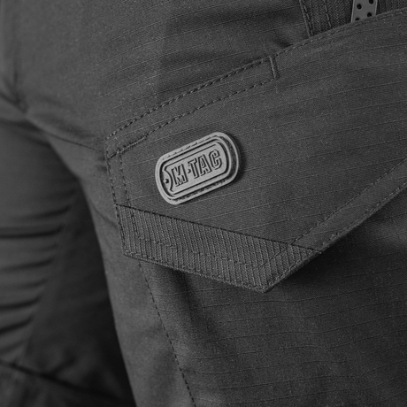 Yksityiskohta M-Tac Shorts Aggressor Shortista näkyvällä taskulla ja M-Tac-logolla, valmistettu kestävästä rip-stop-kankaasta.