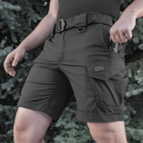 Mies pukeutuneena M-Tac Shorts Aggressor Shortiin, sopii lämpimiin päiviin ja aktiiviseen kaupunkikäyttöön, taktisin ominaisuuksin ja rip-stop-materiaalista.