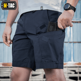 Mies pukeutuneena M-Tac Shorts Aggressor Shortiin taktisin ominaisuuksin, sopii lämpimiin päiviin, suunniteltu joustavasta polycotton Flex rip-stop -materiaalista.