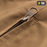 Lähikuva M-Tac Shorts Aggressor Shortista ruskeana YKK-vetoketjulla. Sopii aktiivisille käyttäjille kaupunkiympäristöissä ja luonnossa.