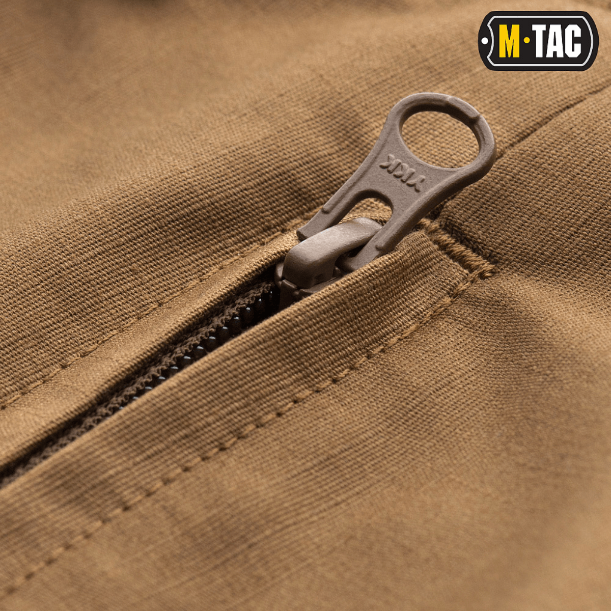 Lähikuva M-Tac Shorts Aggressor Shortista ruskeana YKK-vetoketjulla. Sopii aktiivisille käyttäjille kaupunkiympäristöissä ja luonnossa.