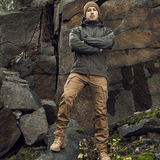 Mies pukeutuneena M-Tac Norman Windblock -fleecetakkiin kallion edessä, kestävä ja tyylikäs ulkovaatetus luonnossa.