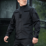 Mies pukeutuneena mustaan M-Tac Patrol Flex -takkiin velcro-paneeleilla, piilotetuilla rintataskuilla ja tuuletusrei'illä taktista käyttöä varten