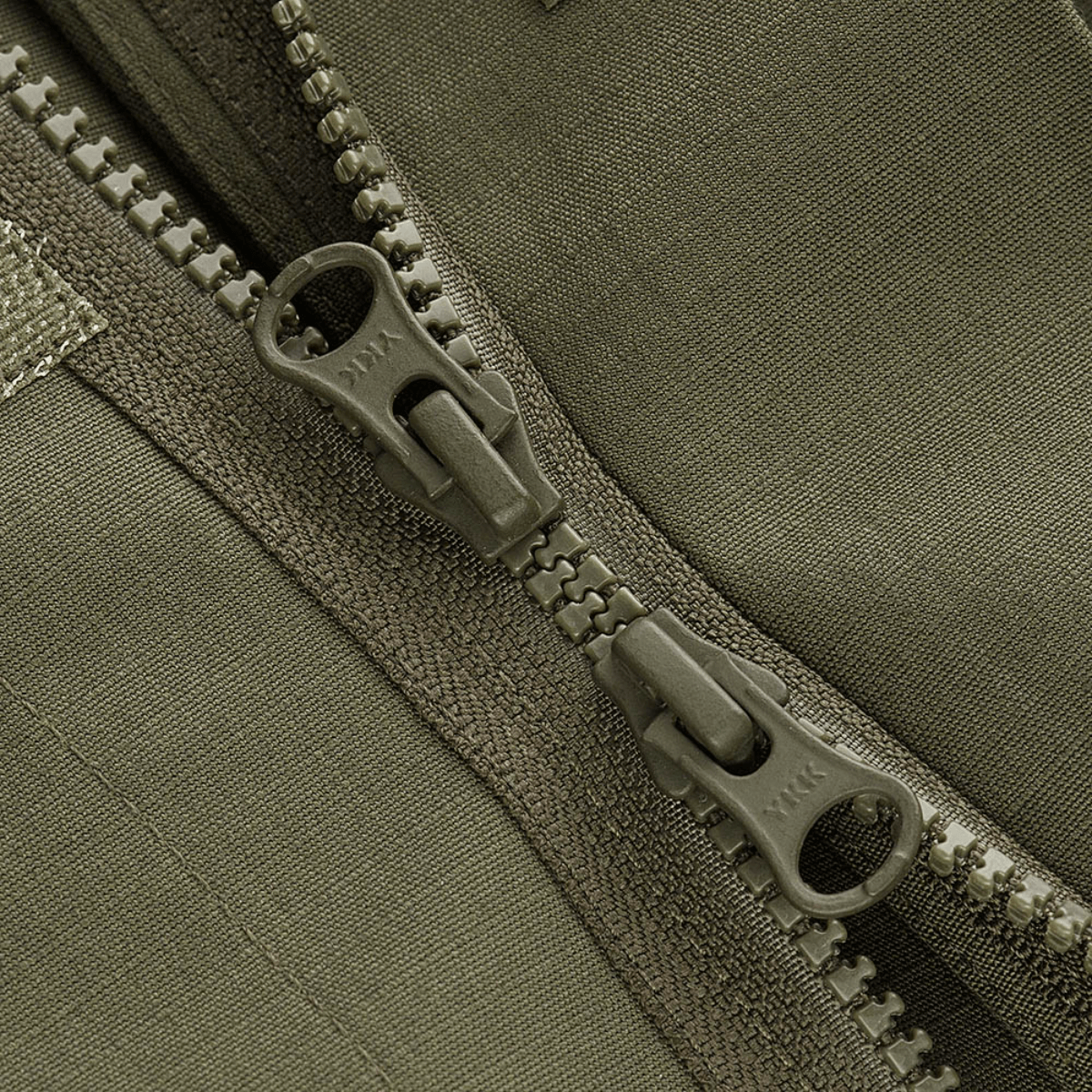 Yksityiskohta M-Tac Patrol Flex -takista kestävästä YKK-vetoketjusta ja Velcro-peitteestä, sopii taktiseen ja käytännölliseen vaatetukseen.