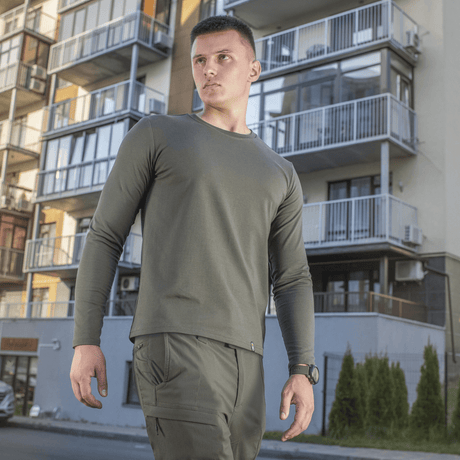 Mies M-Tac Long-sleeve T-shirt 93/7 päällä modernien rakennusten edessä, täydellinen arkeen, univormuihin ja ulkoiluun.