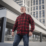 Mies pukeutuneena M-Tac Redneck -paitaan punamustassa ruutukuosissa urbaanissa taustassa, taktinen muotoilu, sopii työhön ja vapaa-aikaan.