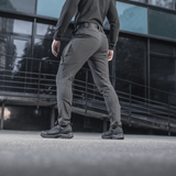 Henkilö pukeutuneena M-Tac Rubicon Flex -housuihin, sopivat harjoitteluun ja työhön, modernissa kaupunkiympäristössä. Mukava 4-Way Stretch -kangas.