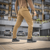 Mies käyttää M-Tac Rubicon Flex -housuja kadulla, esittää liikkumisvapautta 4-Way Stretch -kankaalla ja innovatiivisella cargo-taskusuunnittelulla.