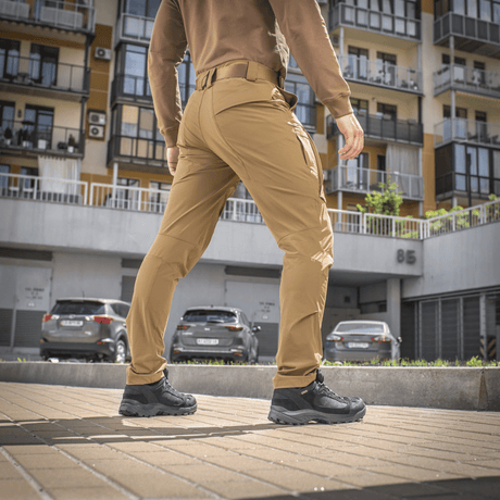 Mies käyttää M-Tac Rubicon Flex -housuja kadulla, esittää liikkumisvapautta 4-Way Stretch -kankaalla ja innovatiivisella cargo-taskusuunnittelulla.
