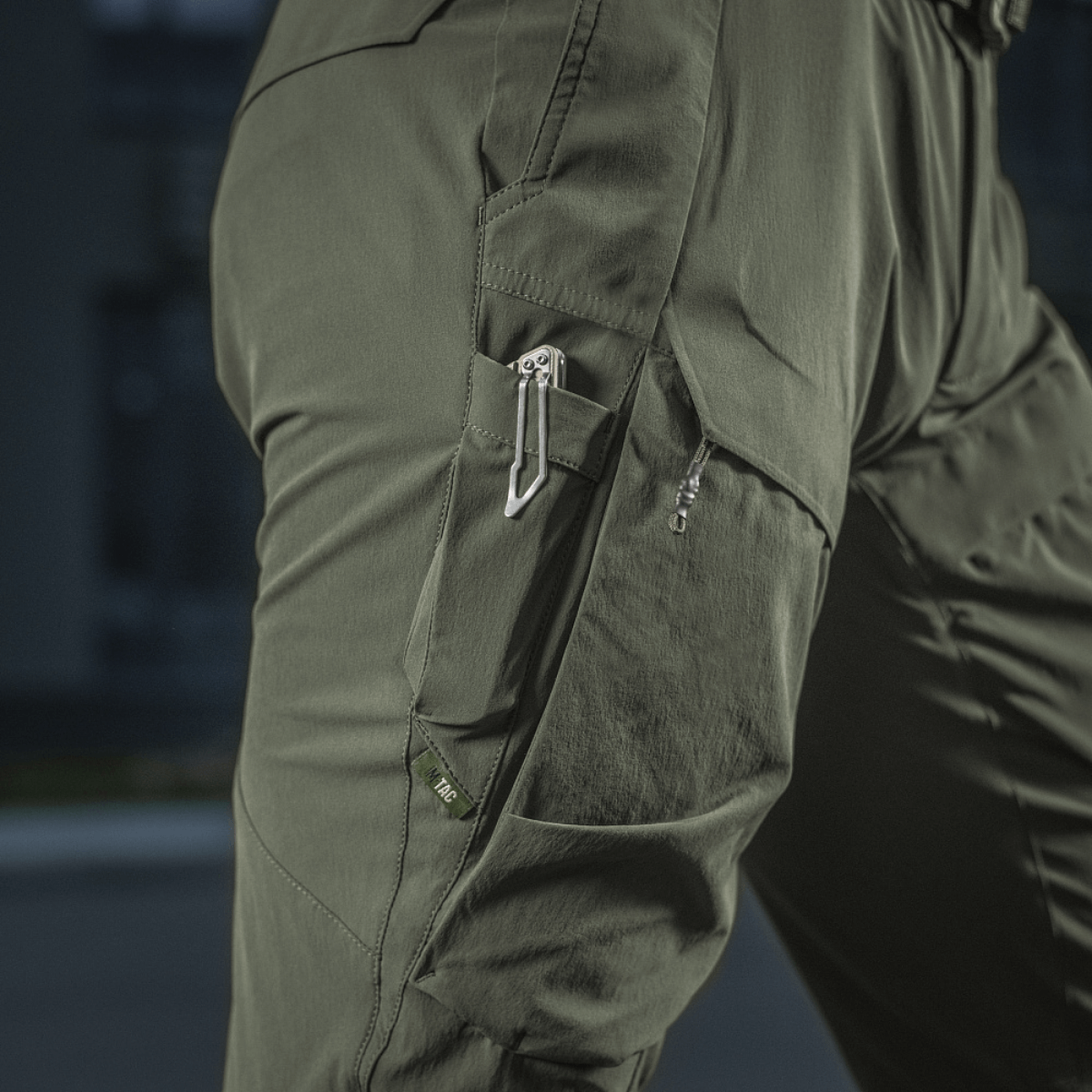 Yksityiskohta M-Tac Rubicon Flex -housuista innovatiivisella cargo-taskusuunnittelulla, sopii ulkoaktiviteetteihin ja treeniin.